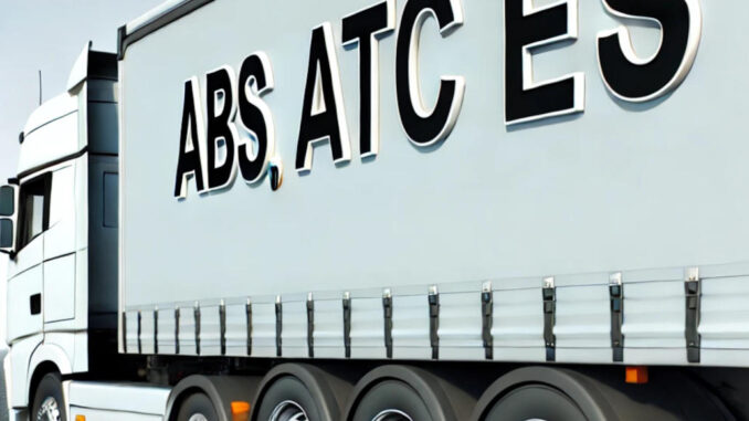 A commercial truck with a trailer on a clear highway, showing the abbreviations ABS, ATC, and ESP visibly printed on the side of the trailer.