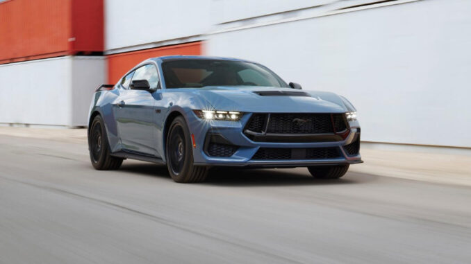 Ein blauer Ford Mustang fährt 2022 an Containern vorbei. Die Ford Motor Company hat die siebte Generation des berühmten Pony-Cars auf der North American International Auto Show (NAIAS) präsentiert. Die jüngste Auflage des meistverkauften Sportwagens der Welt geht erneut als Coupé und Cabriolet an den Start und wird voraussichtlich ab Spätsommer 2023 auch in Deutschland bestellbar sein.