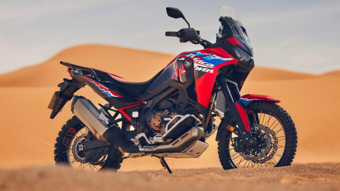 Eine rot-blaue 24YM HONDA CRF1100L AFRICA TWIN steht 2023 in der Wüste.