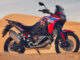 Eine rot-blaue 24YM HONDA CRF1100L AFRICA TWIN steht 2023 in der Wüste.