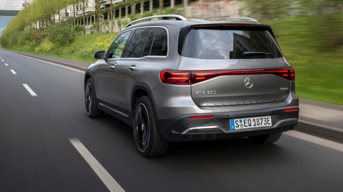 Ein Mercedes-Benz EQB 300 4MATIC, in mountaingrau fährt 2023 auf einer Stadtallee.