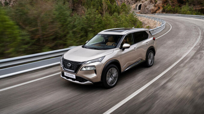 Ein goldener Nissan X-Trail fährt 2022 auf einer Landstraße.